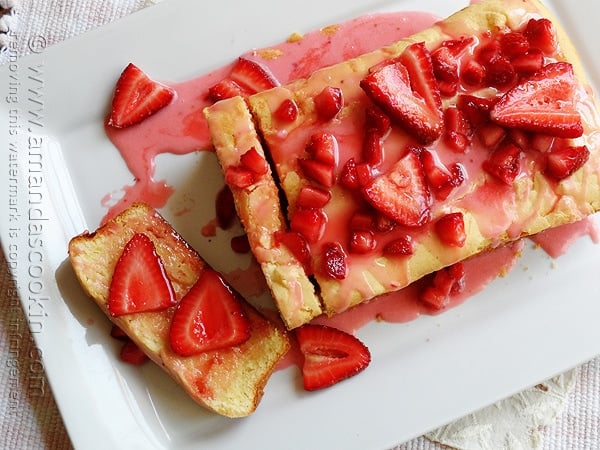 An overhead photo of lemon curd poke cake on a white platter with strawberries on top.