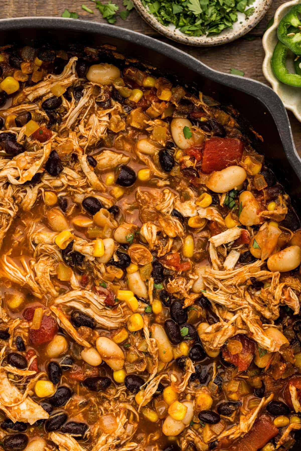 Close up of chicken chili with black beans, cannellini beans, corn and diced tomatoes in a cast iron skillet