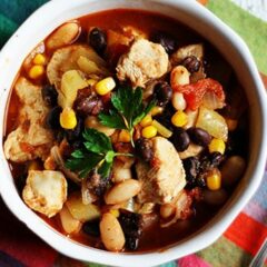 A close up overhead photo of a bowl of chicken chili with black beans and corn.