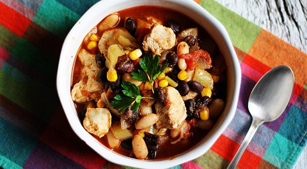A close up overhead photo of a bowl of chicken chili with black beans and corn.