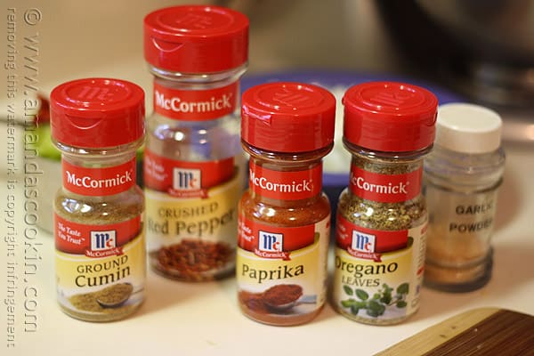 A close up photo of McCormick spice bottles (ground cumin, crushed red pepper, paprika and oregano leaves).