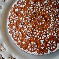 A overhead photo of a Merryfield apple cake on a decorative white platter.