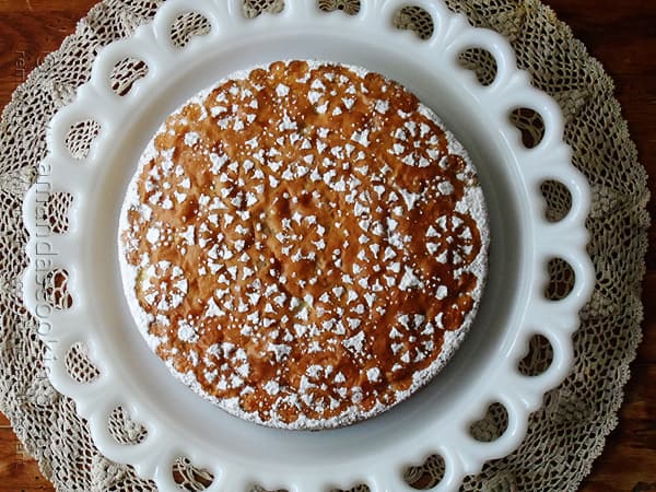 A overhead photo of a Merryfield apple cake on a decorative white platter. 