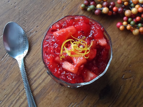 A close up overhead photo of cranberry relish in a glass bowl with a spoon laying next to it.
