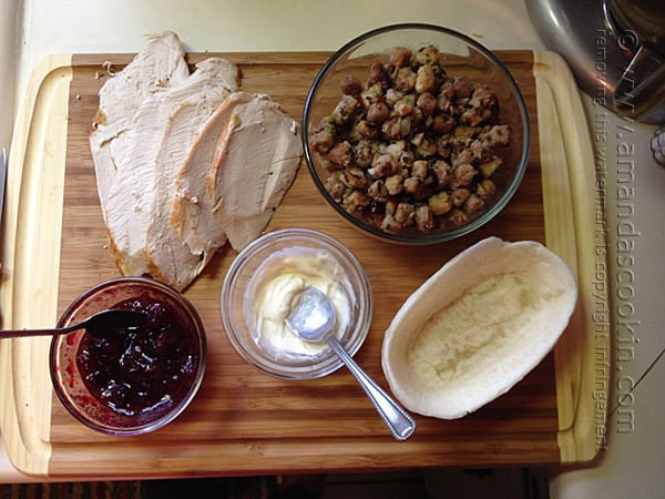 An overhead photo of turkey slices, cranberry, mayonnaise, stuffing and a stand n\' stuff tortilla on a wooden cutting board.