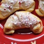 A close up photo of a white chocolate candy cane crescent on a red plate.