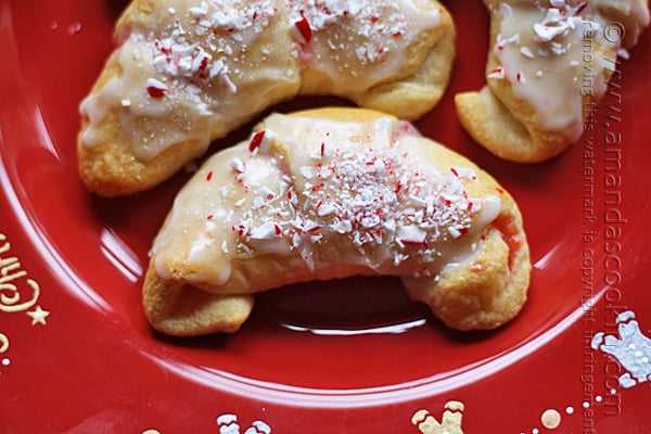 A close up photo of a white chocolate candy cane crescent on a red plate.