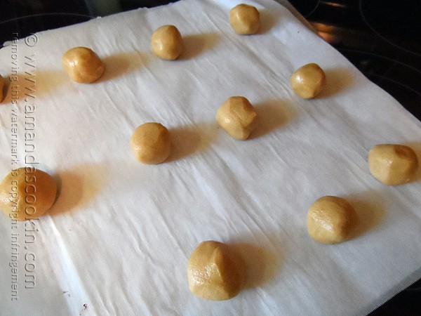 A photo of cookie dough balls on parchment paper.