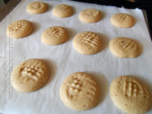 A close up of cooked chocolate filled peanut butter cookies on parchment paper.
