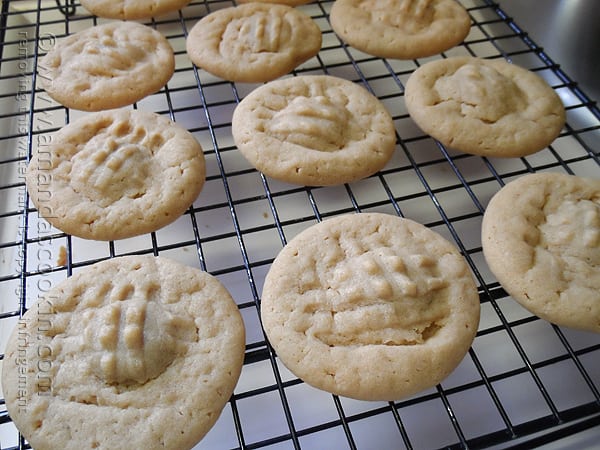 A close up of cooked chocolate filled peanut butter cookies on a wire cooling rack.