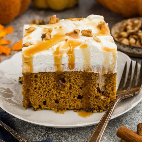 A close up photo of a piece of pumpkin pudding poke cake on a red plate.