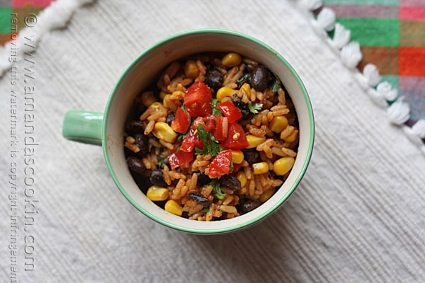 An overhead photo of Spanish rice with black beans and corn in a teal and white bowl.