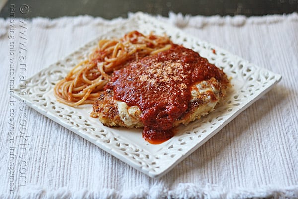 A photo of chicken parmesan on a white decorative plate.