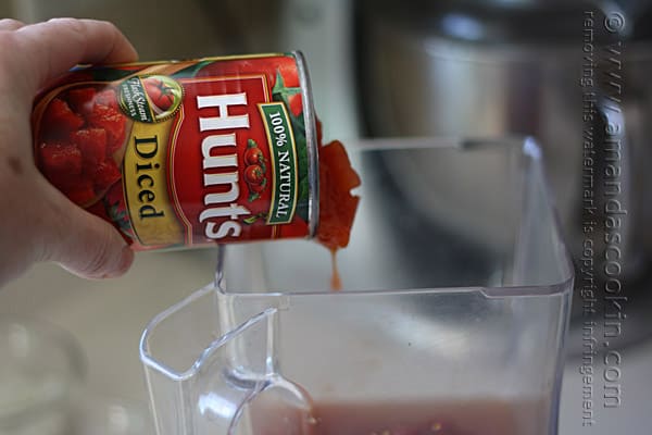 A can of Hunt\'s diced tomatoes being poured into a blender.
