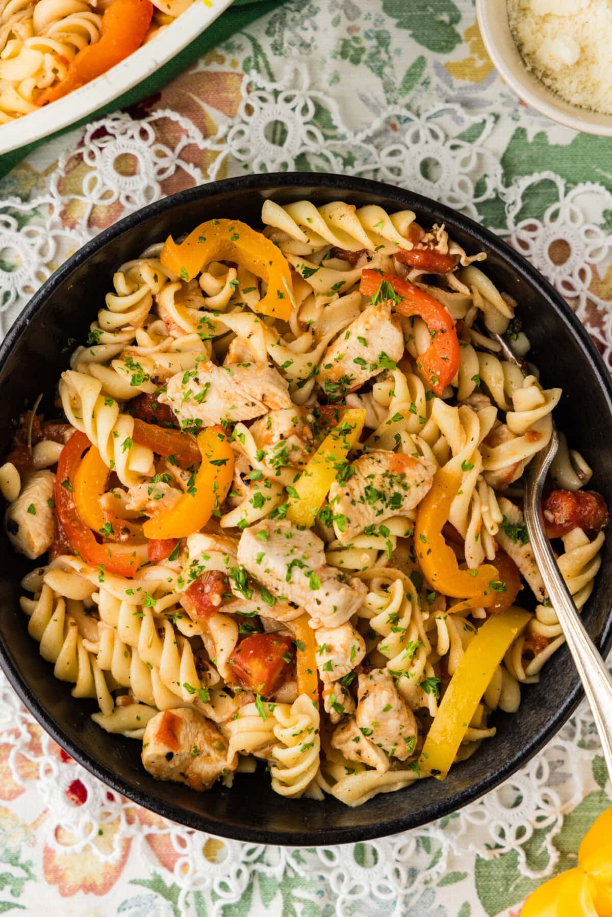 overhead photo of chicken and peppers pasta in black bowl