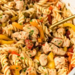 skillet of chicken and peppers pasta with serving spoon