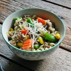 A photo of ramen noodle and beef skillet in a blue and white bowl.