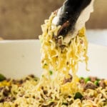 tongs lifting noodles from skillet