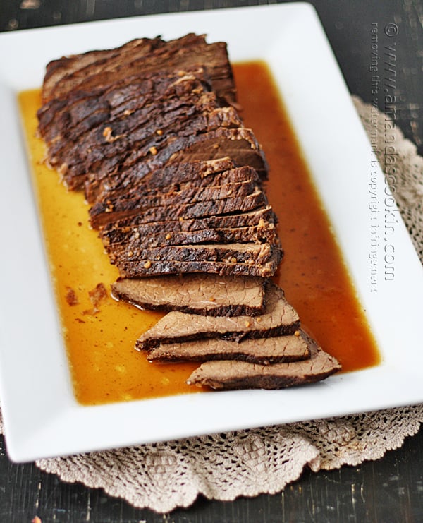 An overhead photo of sliced slow cooker roast with brandy sauce on a white platter.