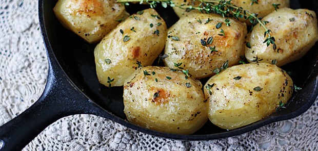 A close up photo of roast potatoes in a cast iron skillet.