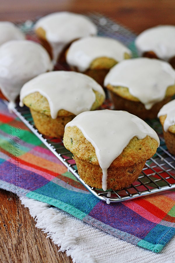 A close up photo of shortcut zucchini muffins resting on a cooling rack topped with sour cream glaze.