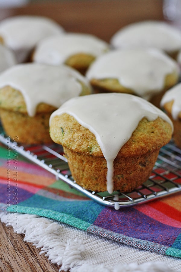 A close up photo of shortcut zucchini muffins resting on a cooling rack topped with sour cream glaze.