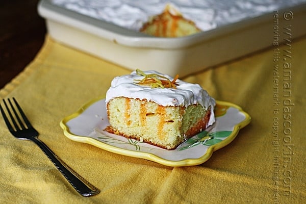 A square of orange and lemon poke cake on a plate.