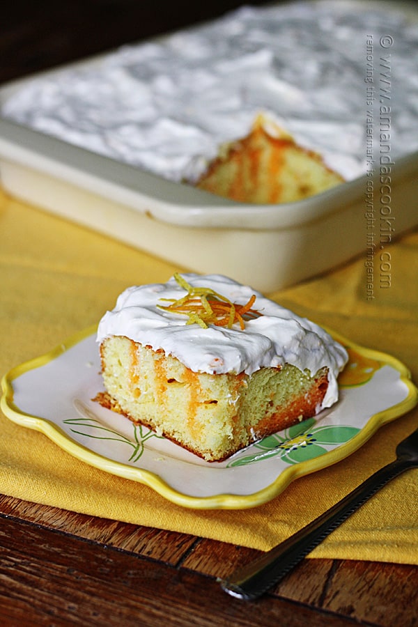 A piece of citrus lover\'s poke cake on a square plate.