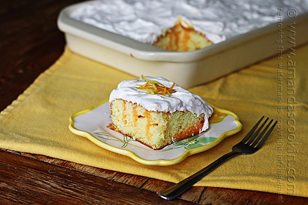 A piece of orange and lemon poke cake on a square plate.