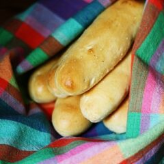 A close up photo of breadsticks in a rainbow colored napkin.