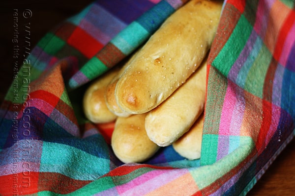 A close up photo of breadsticks in a rainbow colored napkin.