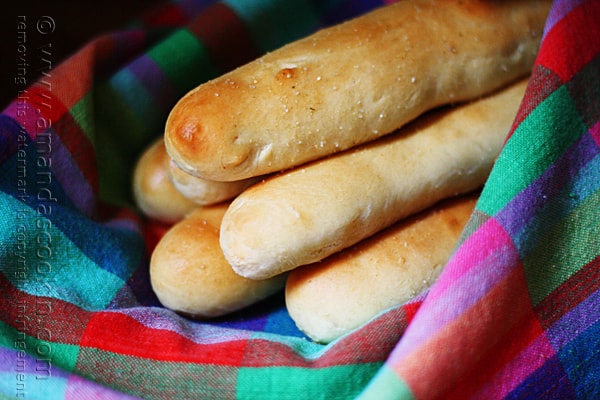 A close up photo of breadsticks in a rainbow colored napkin.