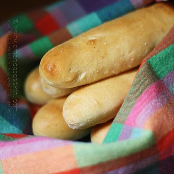 A close up photo of breadsticks in a rainbow colored napkin.