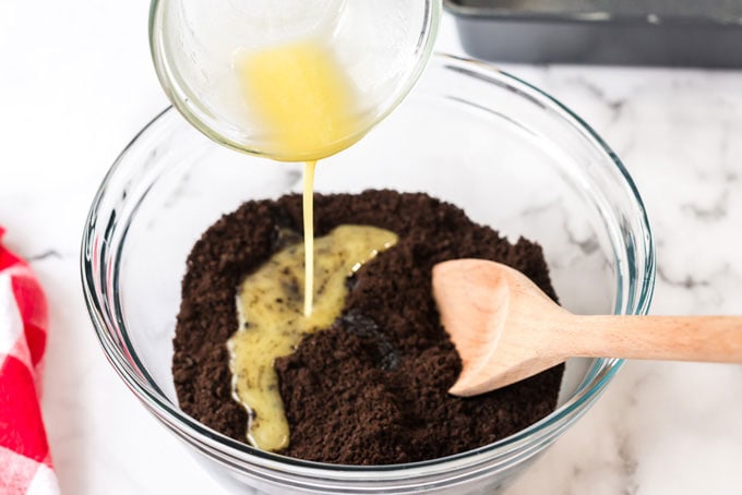 pouring melted butter into chocolate crumbs