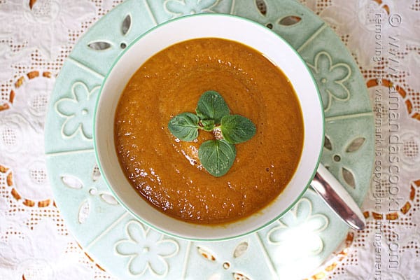 An overhead photo of a bowl of pumpkin soup with fresh parsley on top.