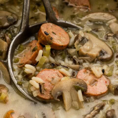 Close up of sausage wild rice soup with mushrooms and celery in a ladle