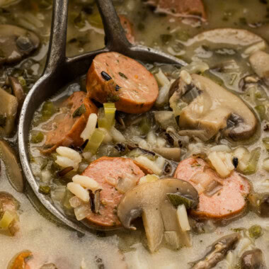 Close up of sausage wild rice soup with mushrooms and celery in a ladle