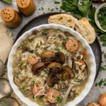 Bowl of wild rice soup with chicken sausage and browned mushrooms topped with Parmesan and parsley, served with crusty bread