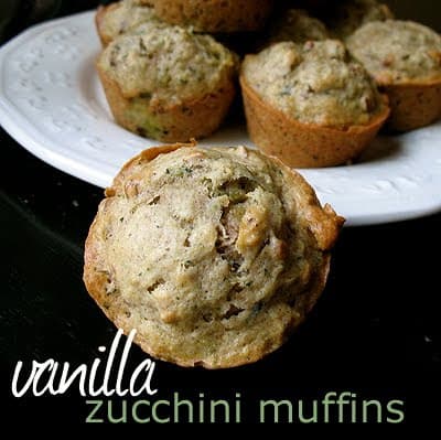 A close up photo of a vanilla zucchini muffin with a plate of them in the background.