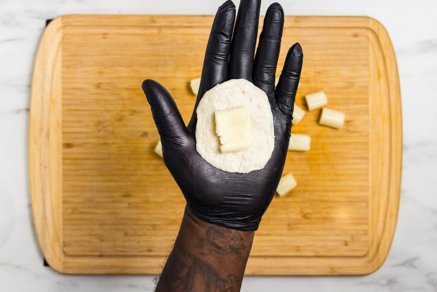hand holding flattened biscuit with cheese stick on it