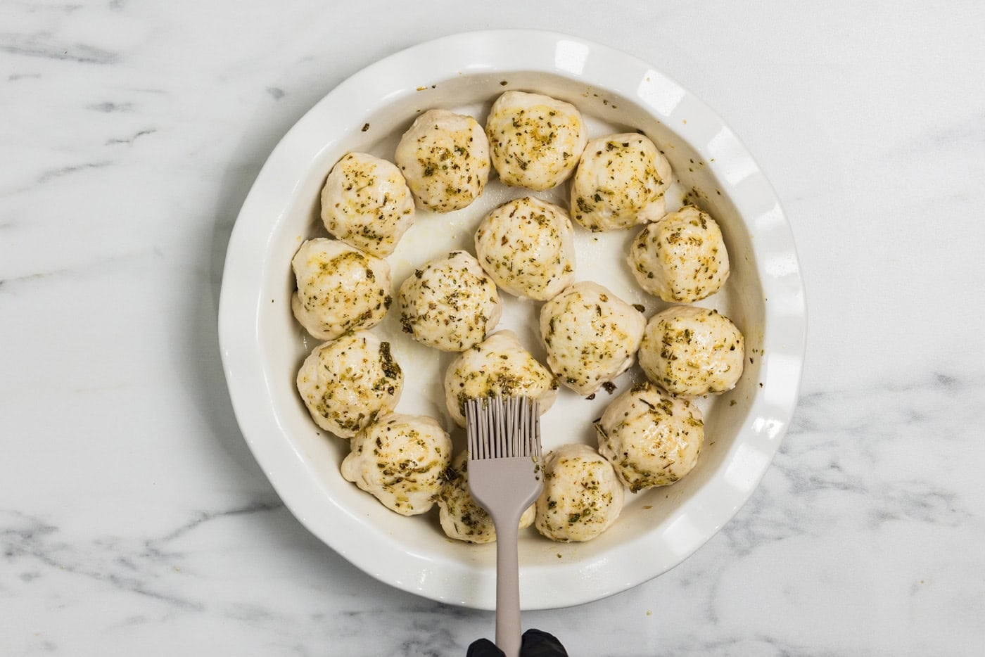 dough balls being brushed with seasoning and oil mixture