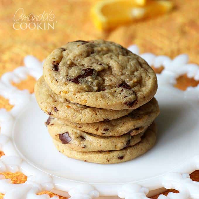 A stack of orange chocolate chip cookies on a white plate.