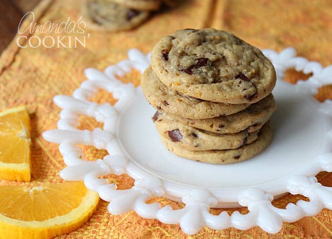 A stack of orange chocolate chip cookies on a white plate.