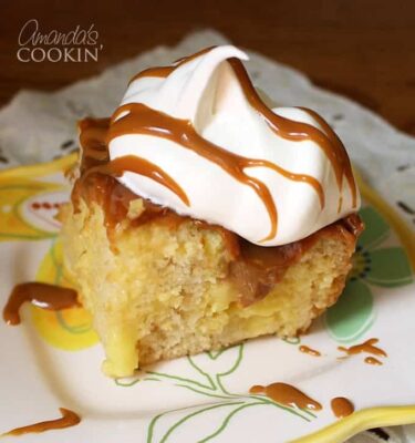 A close up photo of vanilla dream crock pot cake topped with Cool Whip and drizzled Dulce de Leche.