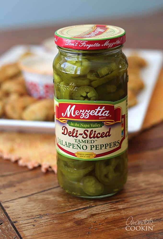 A close up photo of a jar of deli sliced jalapeño peppers.