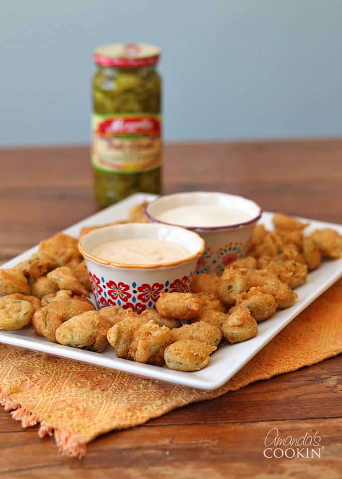 A plate of crispy fried jalapeno slices served with dipping sauces.