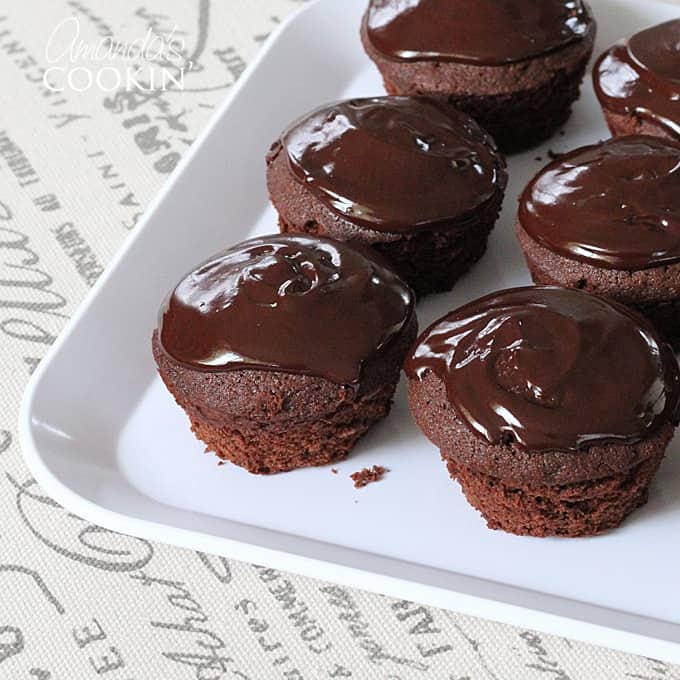 A close up photo of chocolate cupcakes topped with chocolate ganache.