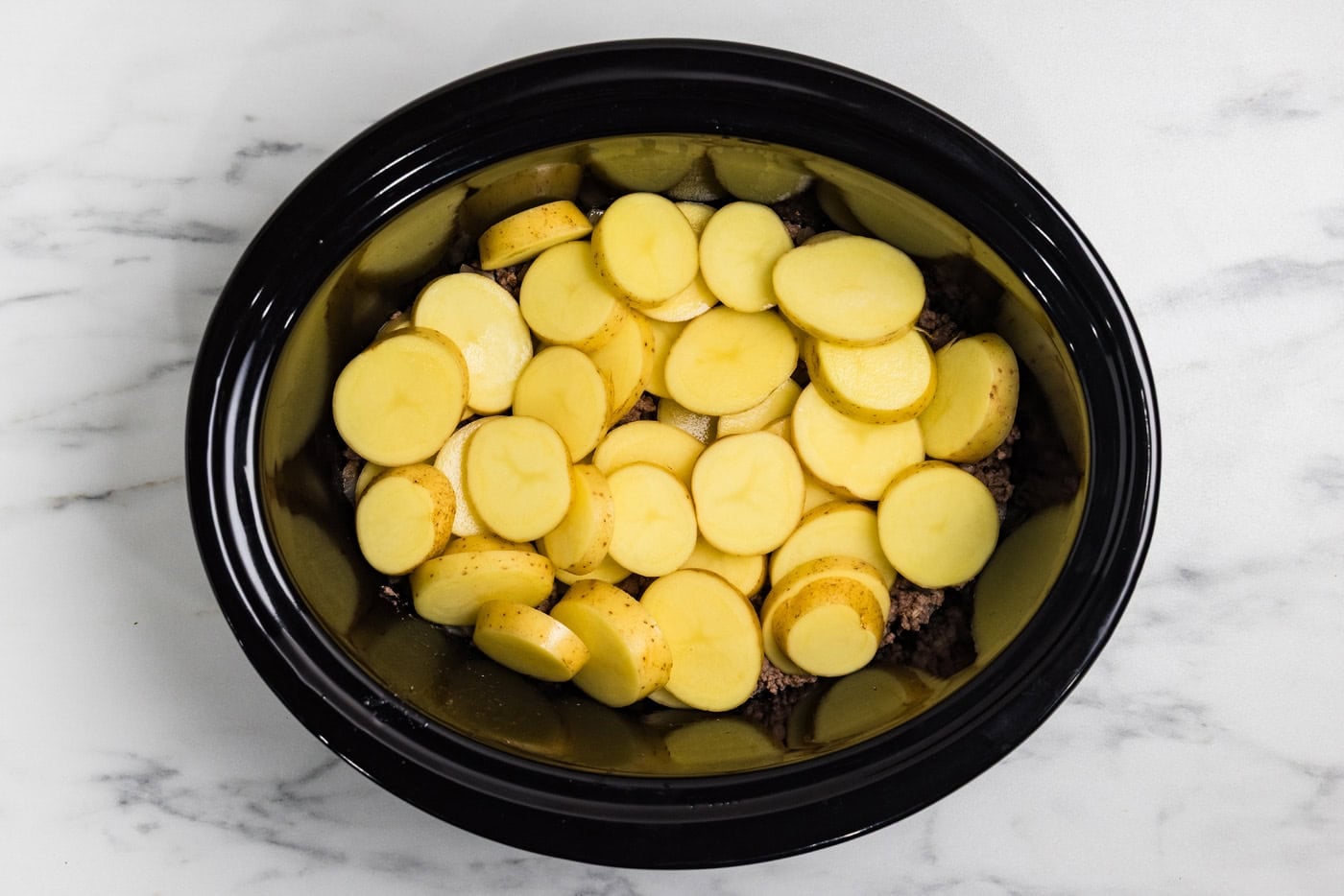 layer of sliced potatoes in crockpot