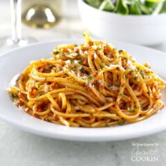 A photo of sun dried tomato pesto on pasta on a white plate.