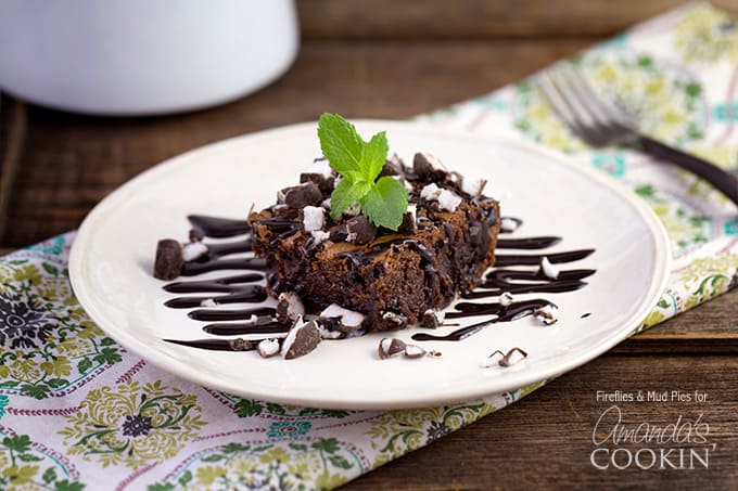 A photo of a peppermint patty brownie topped with drizzled chocolate sauce and a mint leaf.